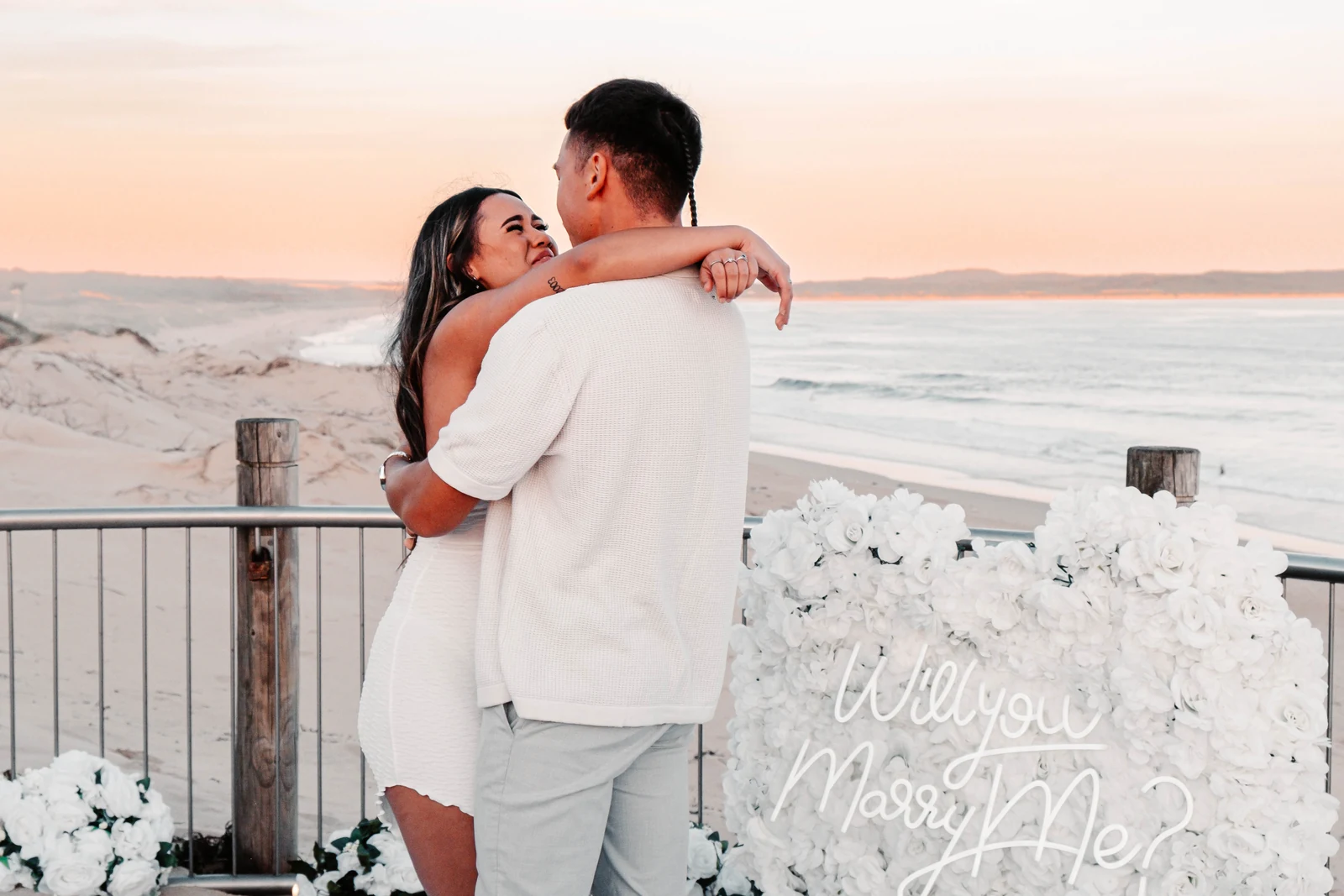 Nini and Nuff embracing by the ocean after a proposal