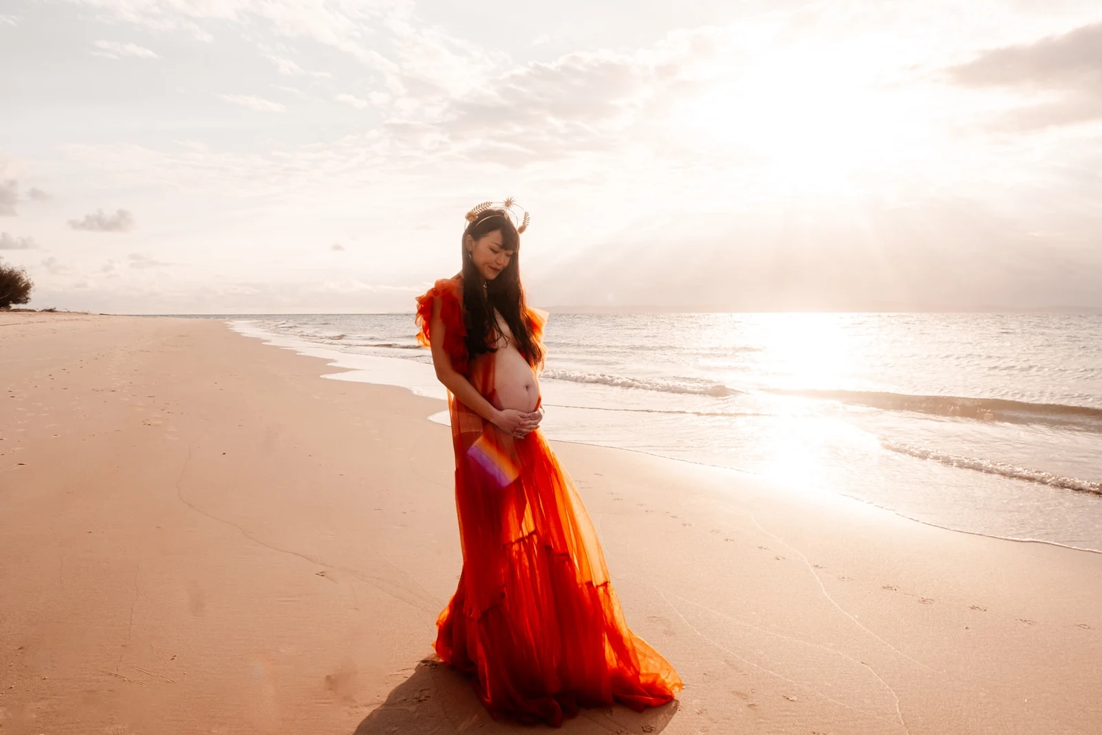Maternity portrait in warm light beside the ocean